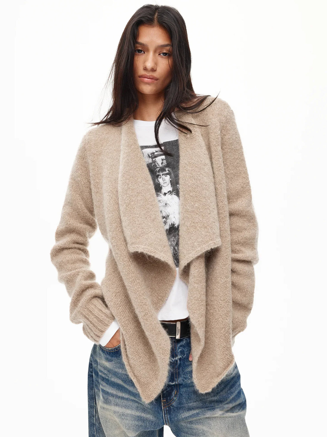 Model in an oatmeal chunky shawl cardigan worn open over a graphic tee and jeans