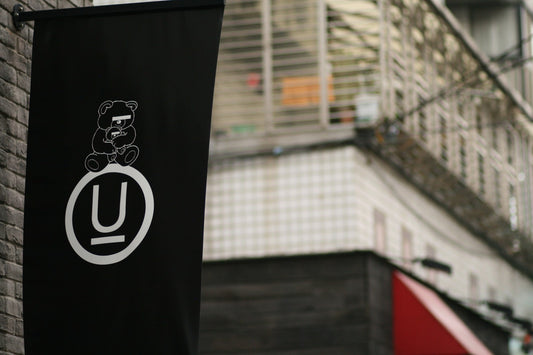Black UNDERCOVER store banner with the Undercover Bear graphic and circled U logo on a brick wall