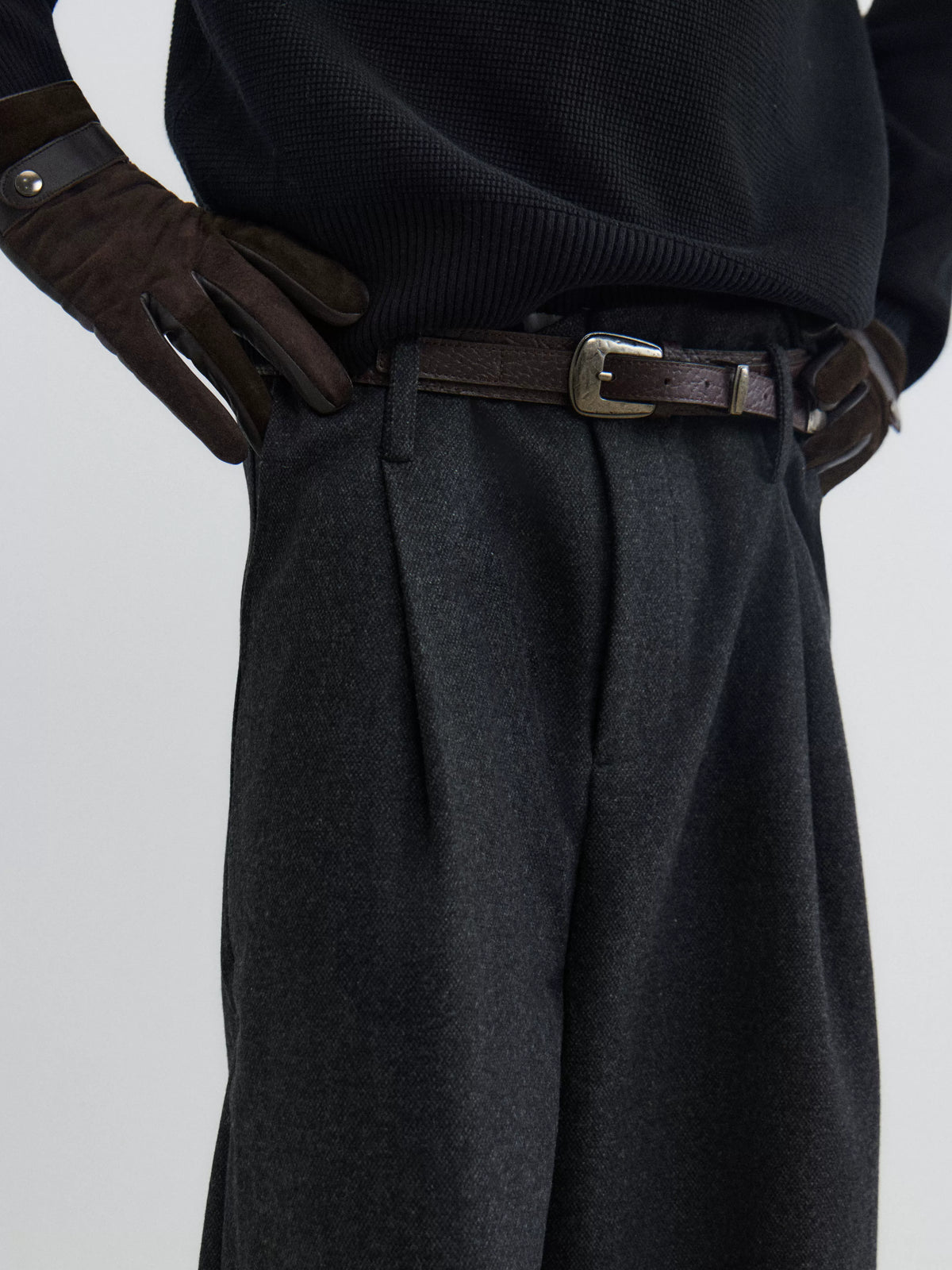 Black textured leather pin buckle belt worn with charcoal pleated trousers
