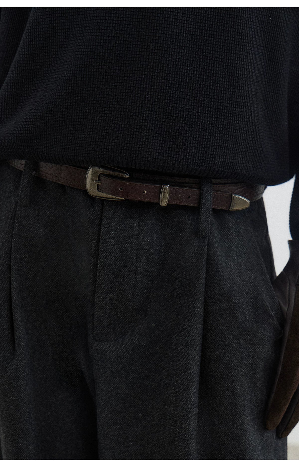 Black textured leather pin buckle belt, close-up at the waist