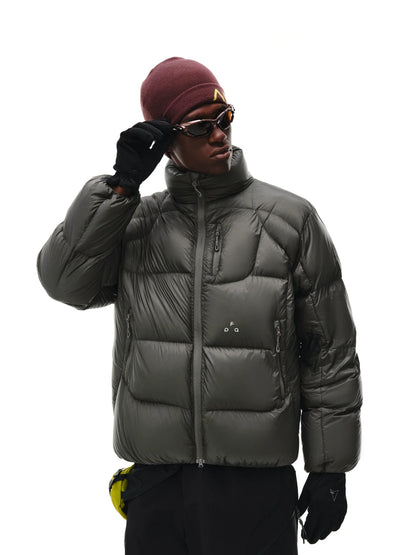 A person in an EastLyst Aurora Puffer Jacket with shiny, lightweight nylon and white duck down, plus black gloves, black pants, a maroon beanie, and sunglasses stands against a white background, adjusting their sunglasses.