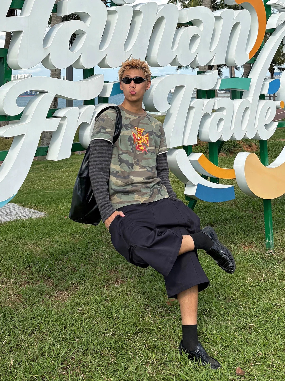 Model wearing the camouflage layered-sleeve shirt, seated outdoors