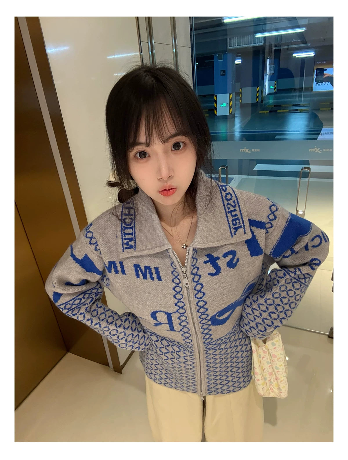 Light grey jacquard cardigan worn with hands at waist