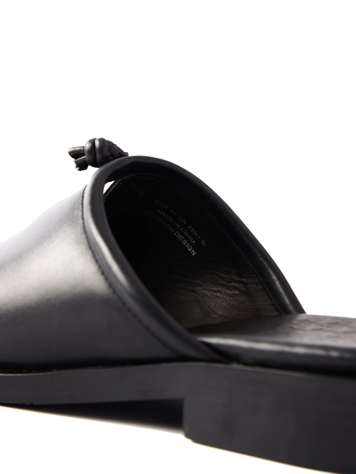 Close-up of a black leather mule from behind, showing the open heel, insole and knot on the vamp