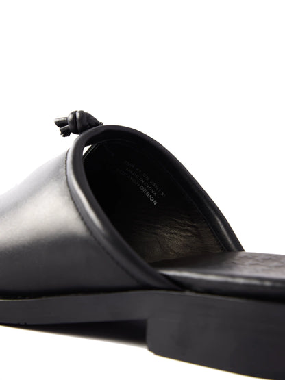 Close-up of a black leather mule from behind, showing the open heel, insole and knot on the vamp