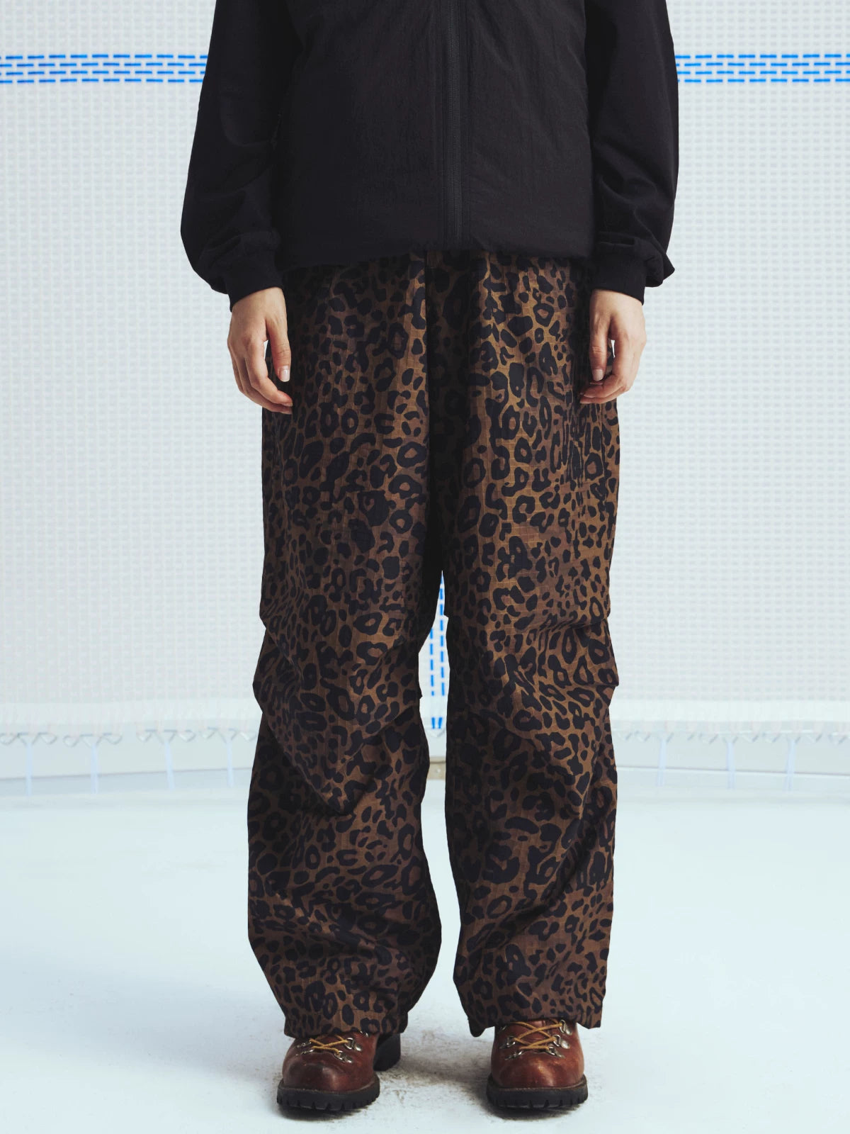 Brown leopard parachute pants worn with a black jacket, front view