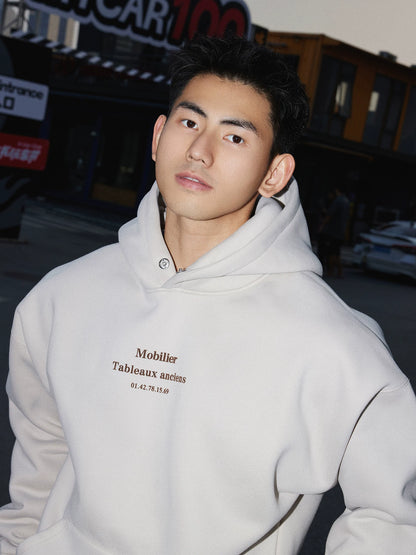 White hooded sweatshirt, chest lettering close view