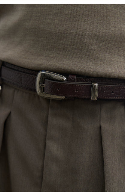 Close-up of the brown textured leather belt's silver pin buckle