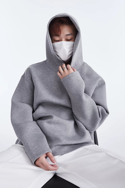 Grey hoodie, seated close front view with hand at neckline