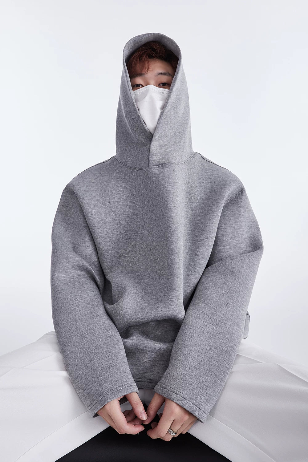 Grey hoodie, seated front view showing hood and button neckline