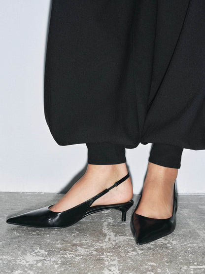 Black kitten-heel slingback pumps worn with black cropped trousers