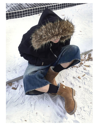 Brown suede winter boots styled with jeans and a dark coat in the snow