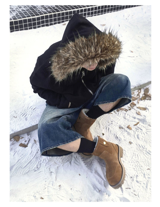 Brown suede winter boots styled with jeans and a dark coat in the snow