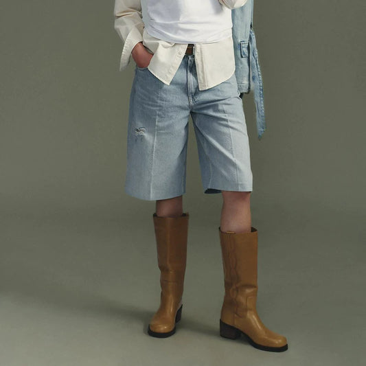 Dark ochre brown embroidered western knee-high boots worn with denim Bermuda shorts