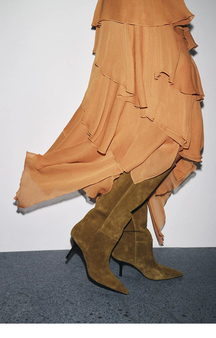 Khaki stiletto knee-high boots styled with an orange tiered skirt