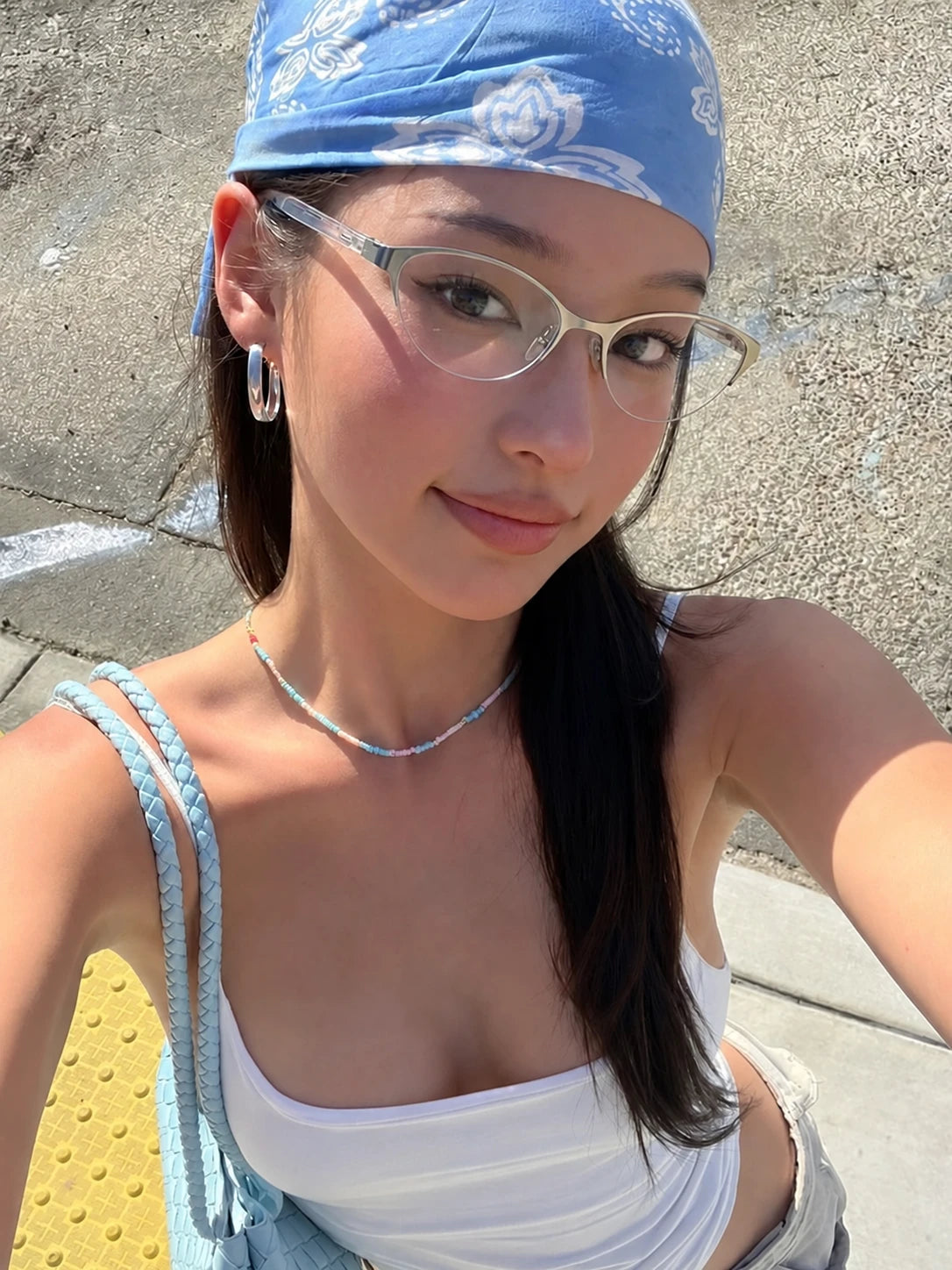 Model wearing silver-tone metal cat-eye glasses and a blue bandana outdoors