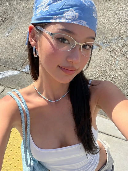 Model wearing silver-tone metal cat-eye glasses and a blue bandana outdoors