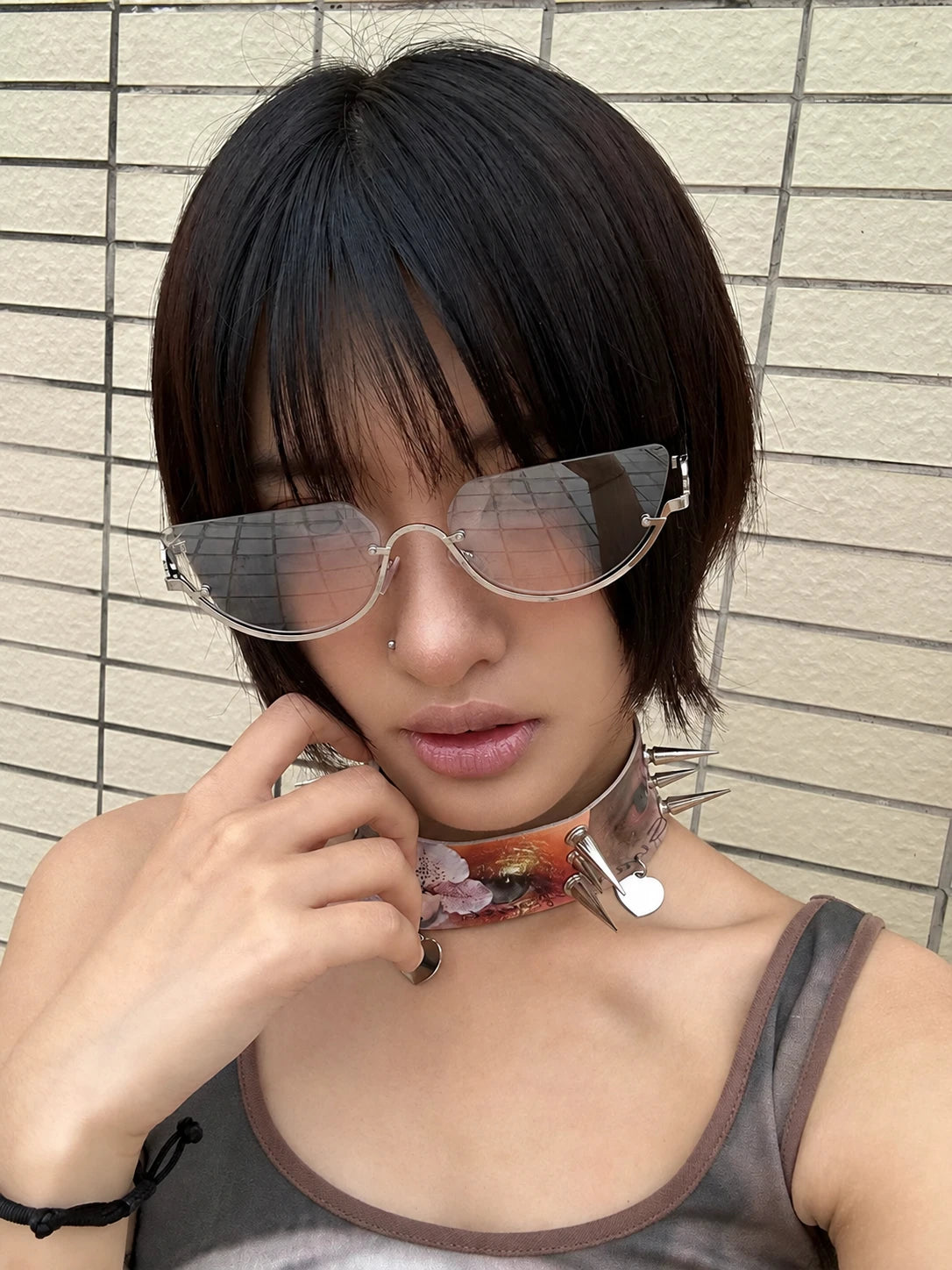 Model wearing silver-tone rounded aviator sunglasses with gradient lenses, with one hand beside the face.