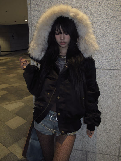 Model wearing a black hooded bomber jacket with a patterned top and denim shorts indoors