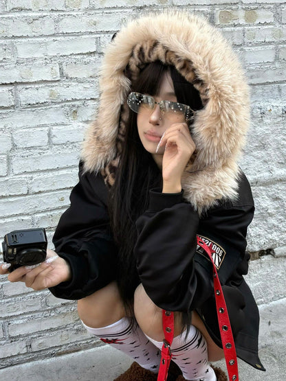 Seated model wearing a black hooded bomber jacket, close view of hood trim and sleeve