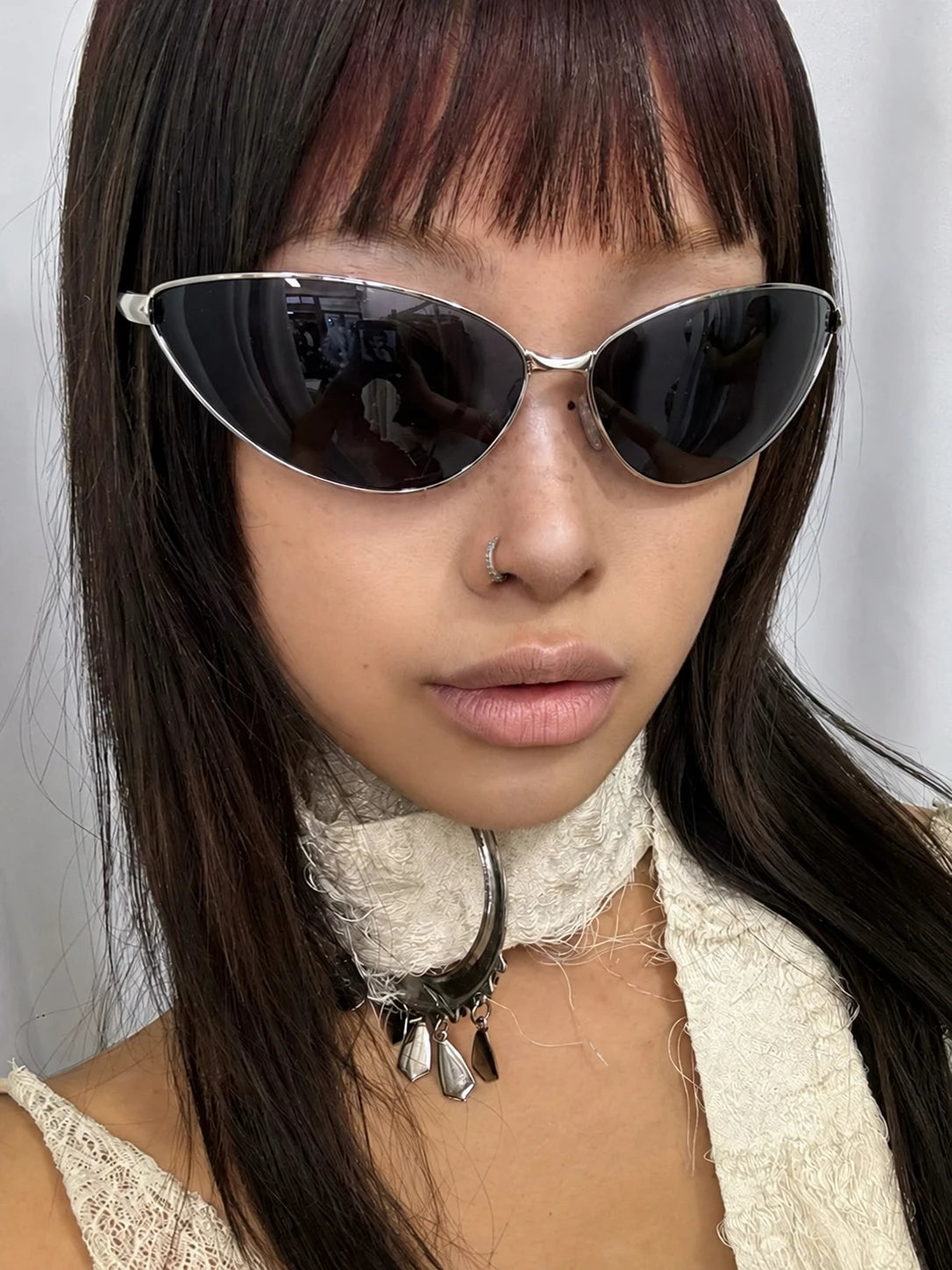 Model wearing silver-tone triangular cat-eye sunglasses with dark lenses.