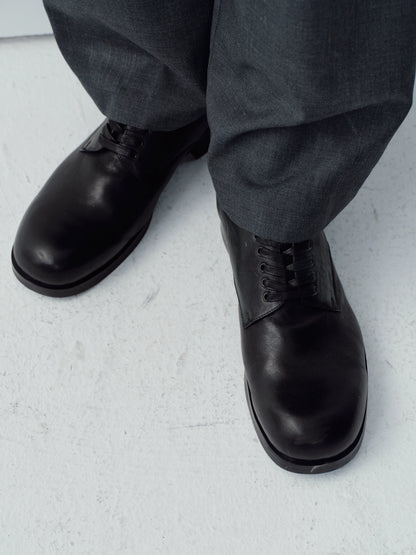 Close top view of Wizard black leather square-toe Derby shoes worn with gray trousers